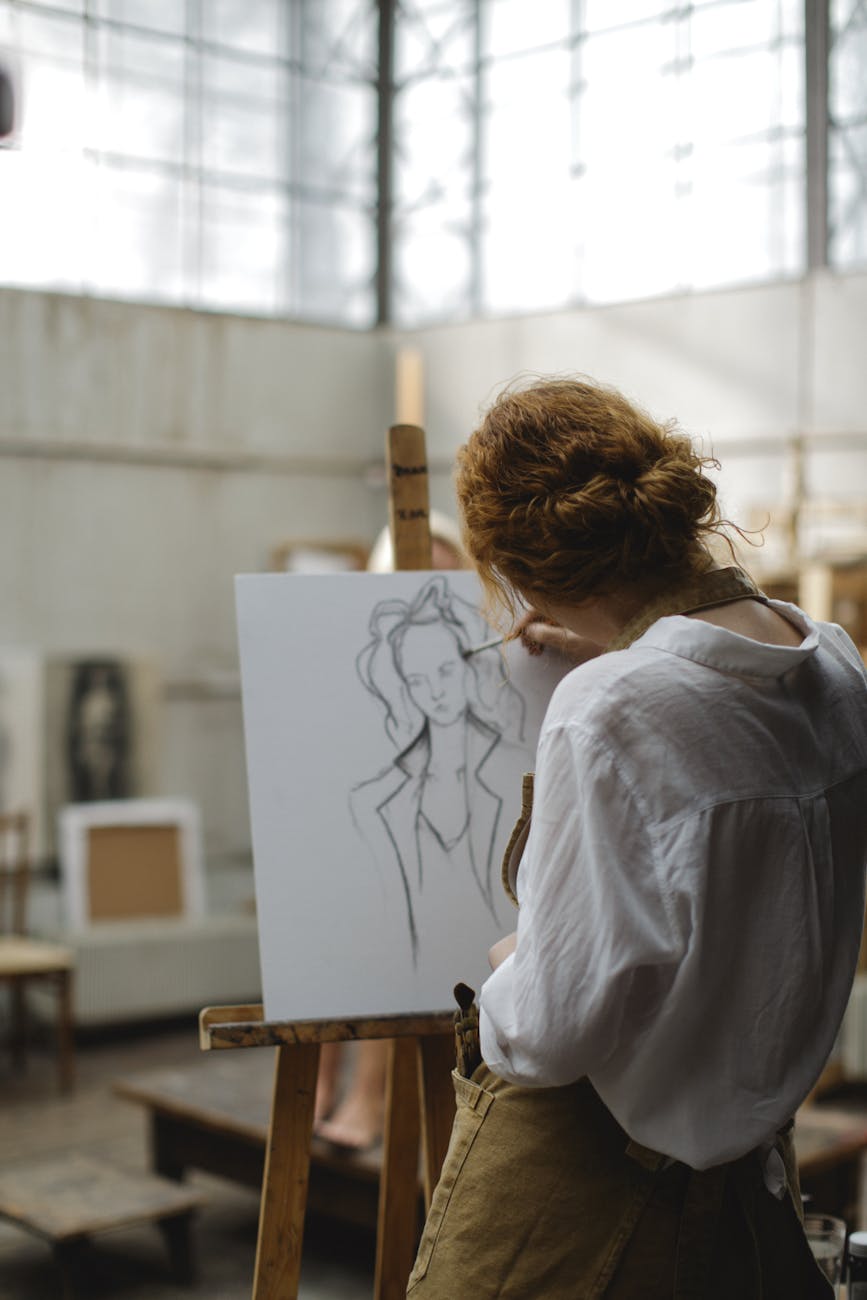 woman in white long sleeves sketching a woman