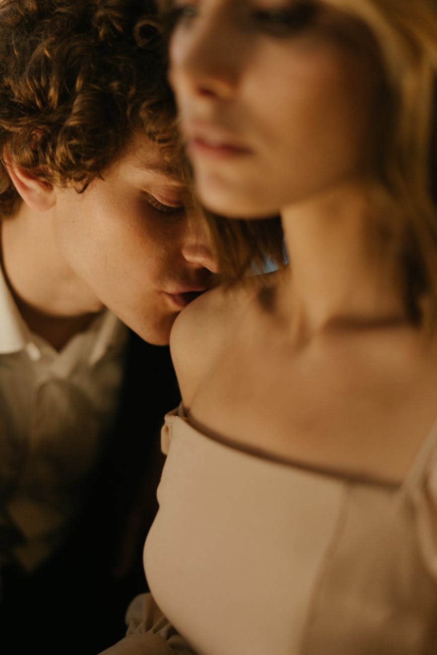 woman in white dress kissing man in gray suit jacket